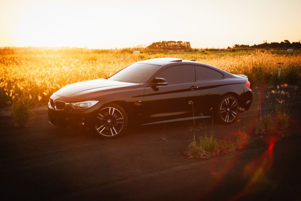 A black sports car parked on a rural road at sunset, capturing the serene beauty and powerful aesthetics.