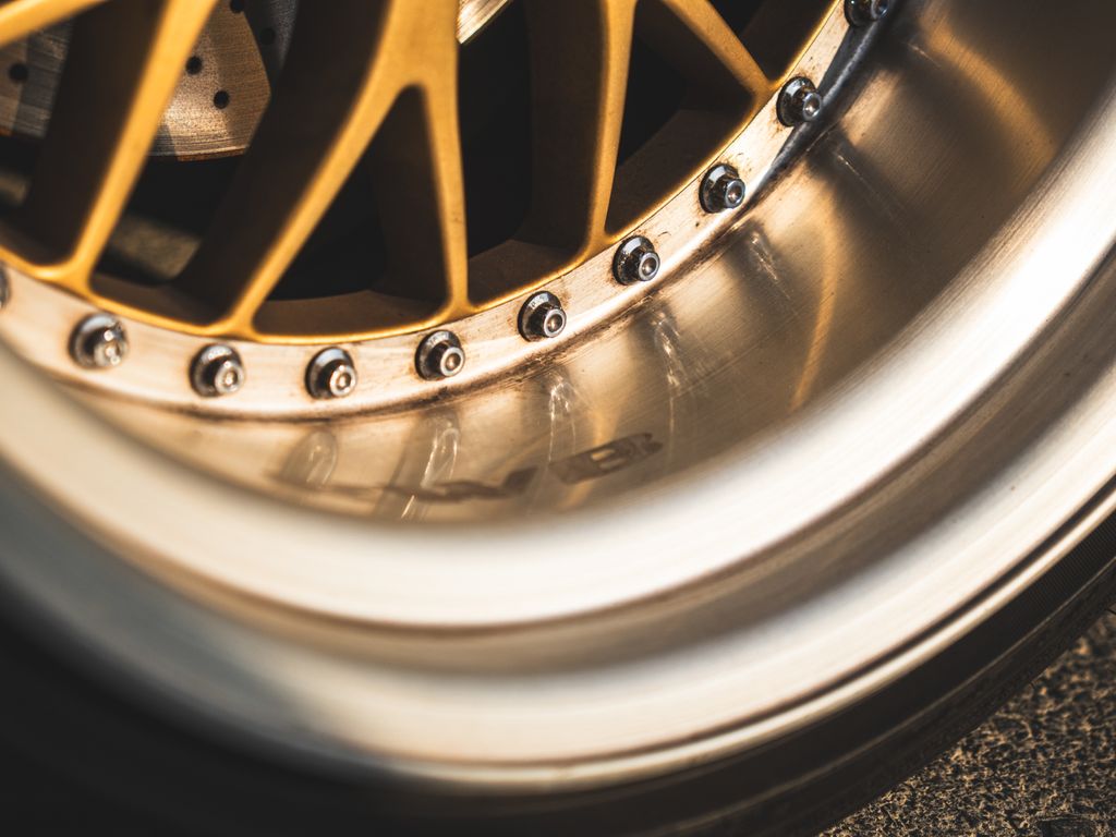 Detailed close-up of a sleek, golden car wheel rim showcasing precision engineering and luxury design.