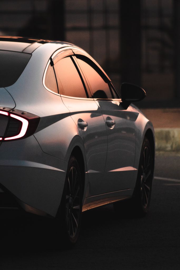 Sleek modern car on city streets during sunset, reflecting urban ambiance.