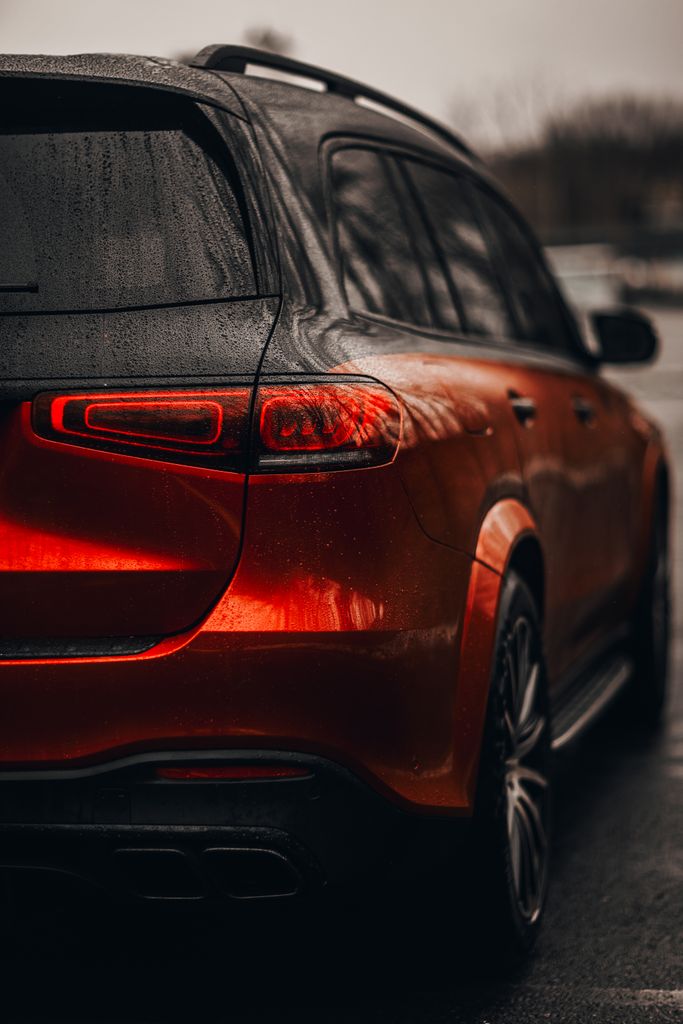 Sleek red SUV captured on a rainy day, showcasing its modern design in a moody setting.