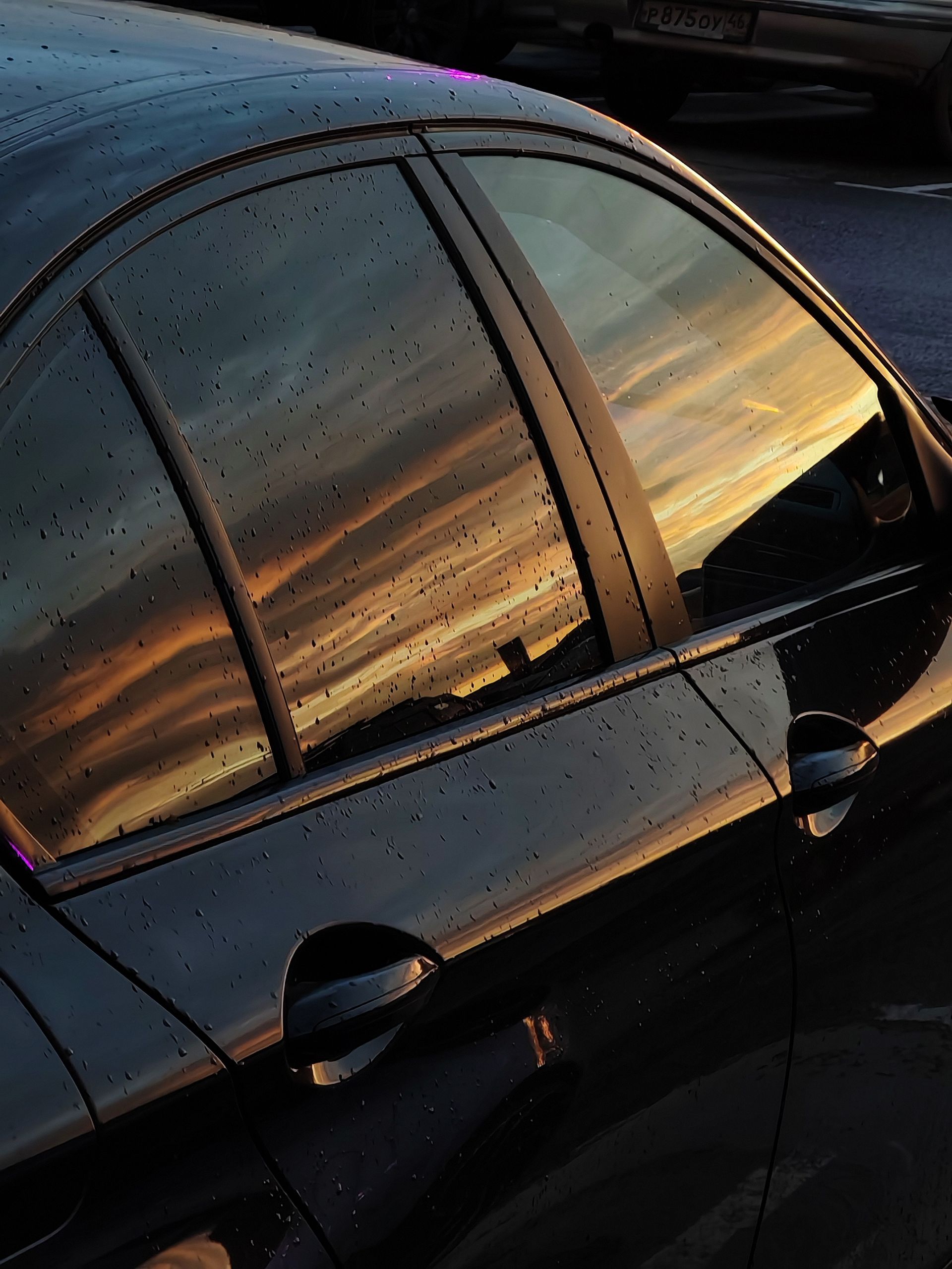 Stunning sunset reflecting on a car window after rain in Moscow, creating a vivid skyline view.